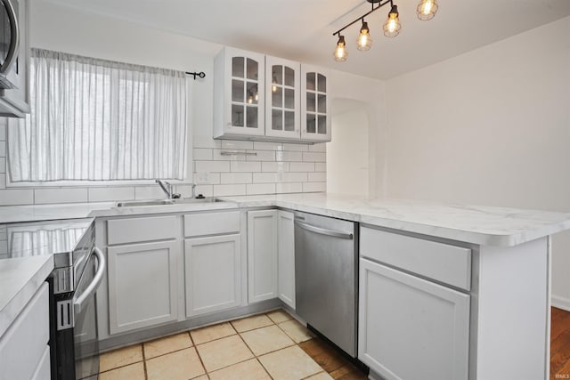 kitchen featuring sink, dishwasher, kitchen peninsula, decorative backsplash, and white cabinets