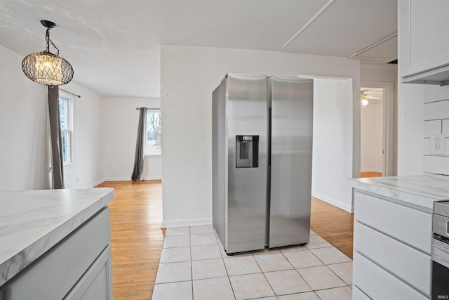 kitchen featuring stainless steel refrigerator with ice dispenser, decorative light fixtures, light stone countertops, and light wood-type flooring