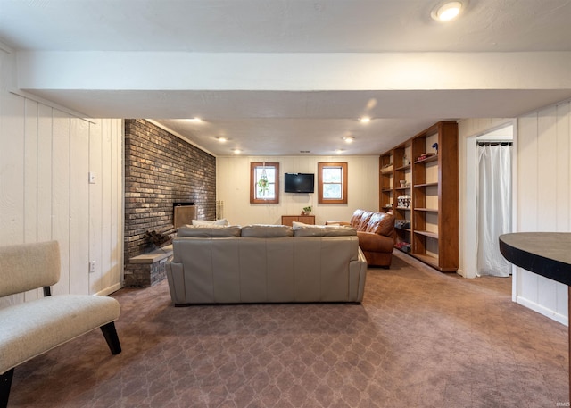 living room featuring a fireplace, wooden walls, and dark colored carpet