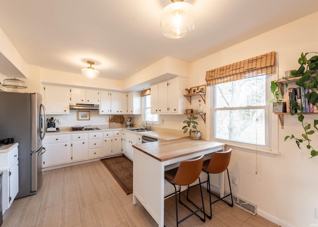 kitchen featuring white cabinetry, appliances with stainless steel finishes, a breakfast bar area, and kitchen peninsula