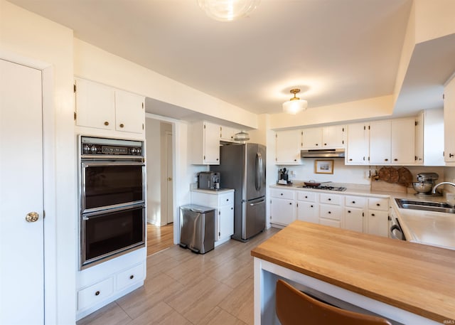 kitchen featuring white cabinetry, appliances with stainless steel finishes, kitchen peninsula, and sink