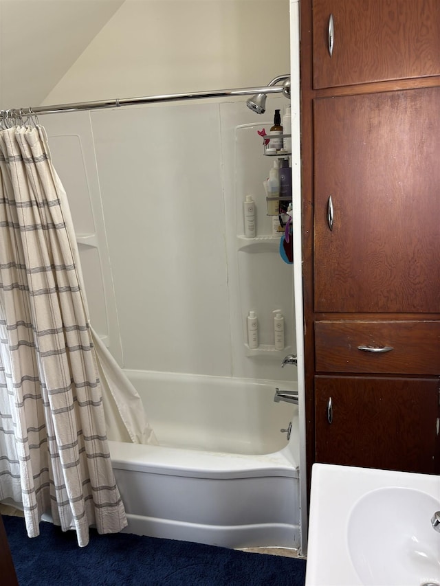 bathroom featuring shower / tub combo with curtain, sink, and lofted ceiling