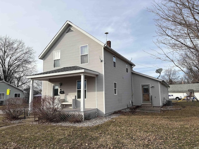 rear view of house featuring a porch and a lawn