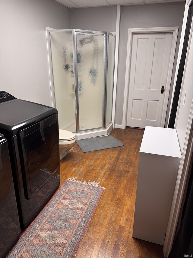 bathroom with wood-type flooring, toilet, washer and clothes dryer, and walk in shower