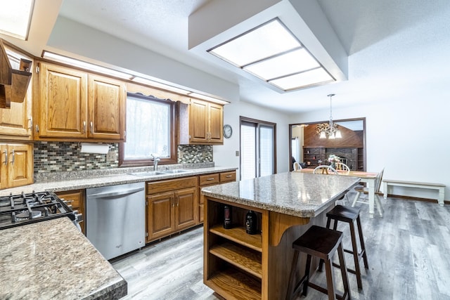 kitchen featuring a kitchen bar, sink, a center island, hanging light fixtures, and dishwasher