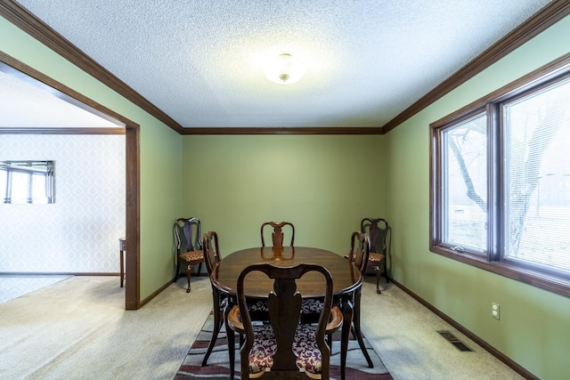 dining room with ornamental molding, carpet, and a textured ceiling