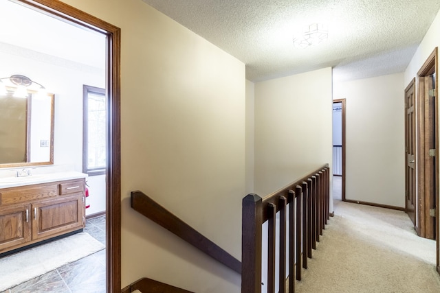 hall featuring sink, light carpet, and a textured ceiling