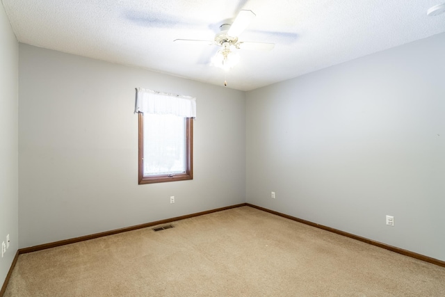 carpeted spare room featuring a textured ceiling and ceiling fan