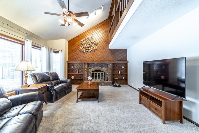 living room featuring high vaulted ceiling, a fireplace, wooden walls, carpet, and ceiling fan