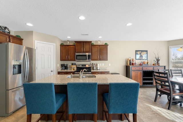 kitchen featuring appliances with stainless steel finishes, sink, a breakfast bar, and a kitchen island with sink