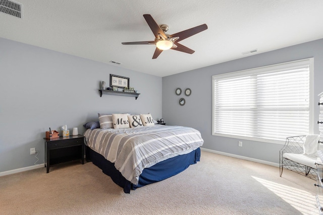 bedroom featuring ceiling fan, light colored carpet, and a textured ceiling