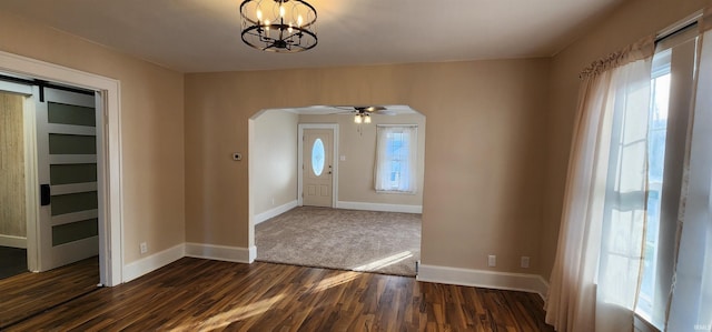 foyer entrance with ceiling fan with notable chandelier, dark wood-type flooring, a barn door, and a healthy amount of sunlight