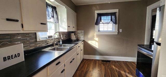 kitchen with tasteful backsplash, stainless steel range with electric cooktop, sink, and white cabinets