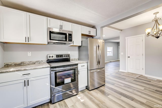 kitchen featuring pendant lighting, light hardwood / wood-style flooring, appliances with stainless steel finishes, a notable chandelier, and white cabinets