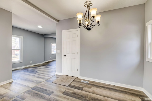 unfurnished dining area featuring wood-type flooring and a chandelier