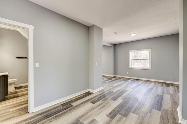 empty room with light hardwood / wood-style floors and a textured ceiling