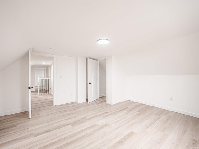 additional living space featuring baseboards, lofted ceiling, and light wood-style flooring