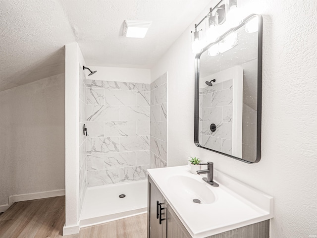 bathroom with a textured ceiling, wood finished floors, a stall shower, and vanity