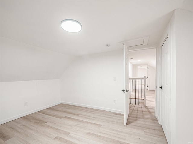 bonus room with light wood finished floors, baseboards, lofted ceiling, and attic access