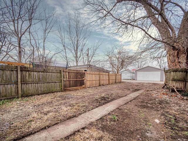 view of yard featuring an outbuilding, a garage, and fence
