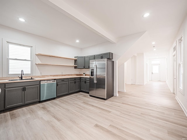 kitchen with light wood finished floors, gray cabinetry, a sink, and stainless steel appliances