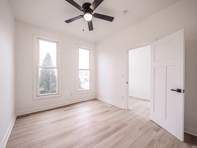 spare room featuring baseboards, light wood-style floors, ceiling fan, and visible vents