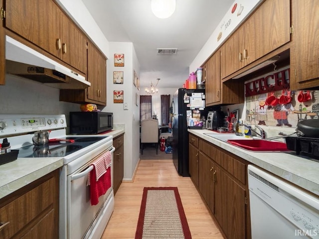 kitchen featuring sink, a notable chandelier, light hardwood / wood-style floors, and black appliances