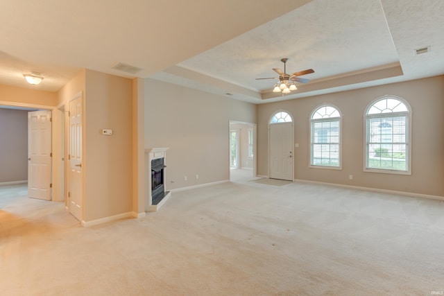 unfurnished living room with a textured ceiling, light colored carpet, a raised ceiling, and ceiling fan