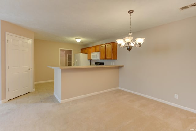 kitchen with a chandelier, light colored carpet, kitchen peninsula, pendant lighting, and white appliances