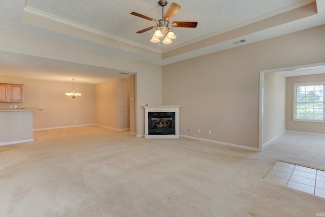 unfurnished living room with light colored carpet, ornamental molding, a raised ceiling, and ceiling fan with notable chandelier