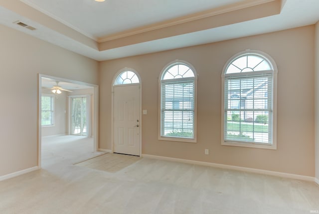 foyer featuring crown molding, light colored carpet, and a tray ceiling