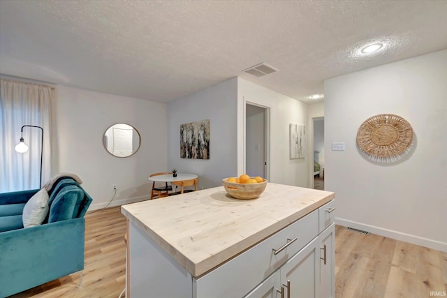 kitchen with a center island, a textured ceiling, light hardwood / wood-style flooring, and white cabinets