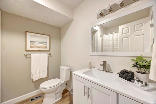 bathroom with vanity, wood-type flooring, and toilet