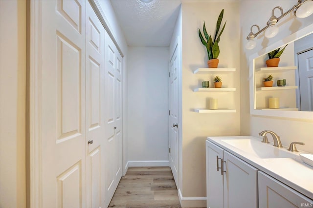 laundry room featuring sink, light hardwood / wood-style floors, and a textured ceiling