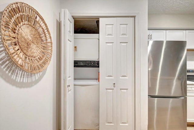 kitchen with a textured ceiling, stainless steel fridge, and white cabinets