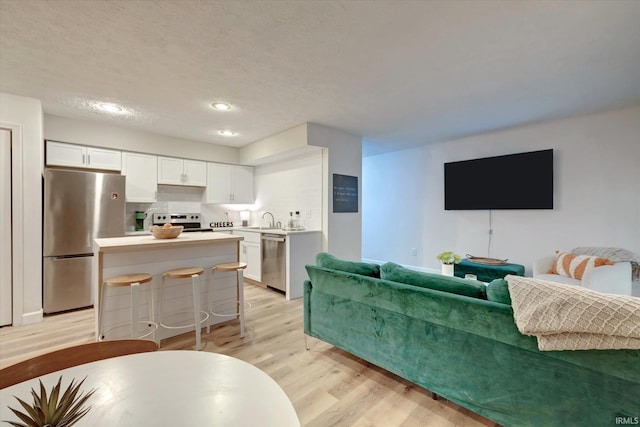 living room featuring sink, light hardwood / wood-style flooring, and a textured ceiling