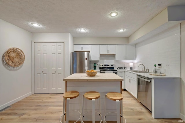 kitchen featuring white cabinetry, appliances with stainless steel finishes, a kitchen breakfast bar, and sink