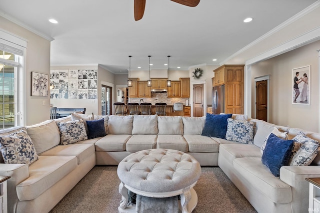 carpeted living room with crown molding and ceiling fan