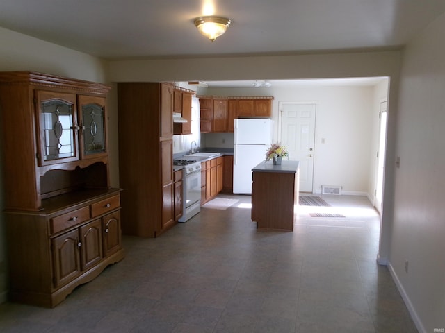 kitchen featuring white appliances, a center island, and sink