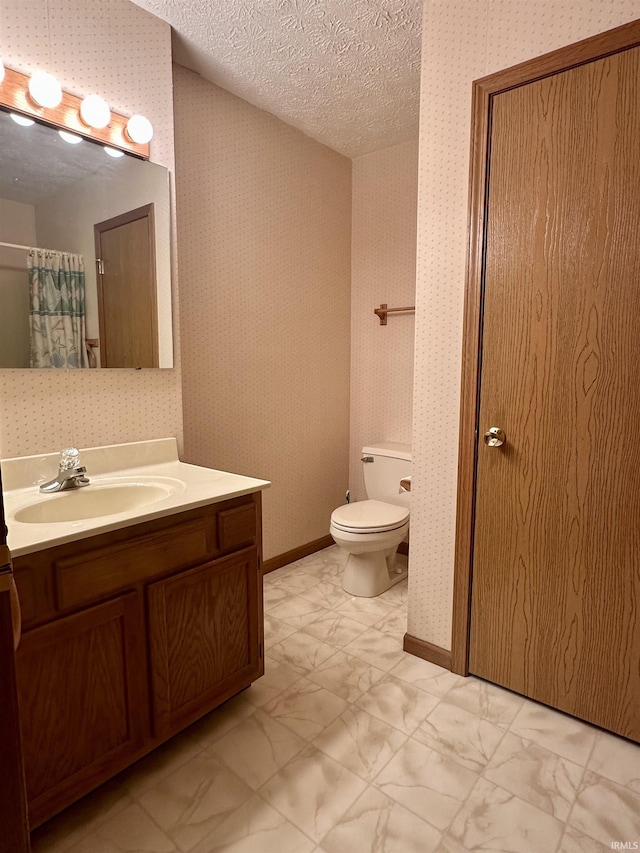 bathroom with vanity, toilet, and a textured ceiling