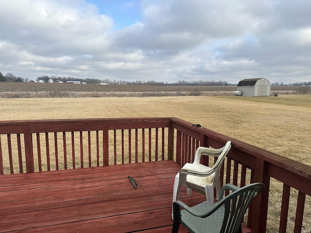 wooden terrace with a storage unit, a lawn, and a rural view