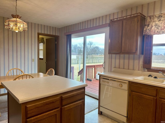 kitchen featuring dishwasher, sink, a chandelier, hanging light fixtures, and a textured ceiling