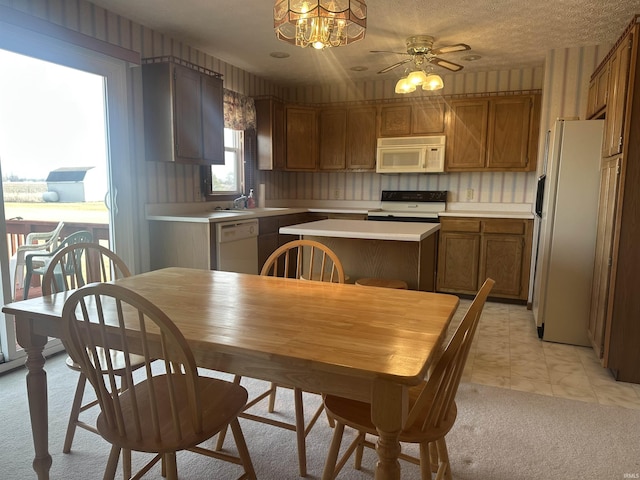 kitchen featuring sink, light colored carpet, white appliances, ceiling fan, and a textured ceiling