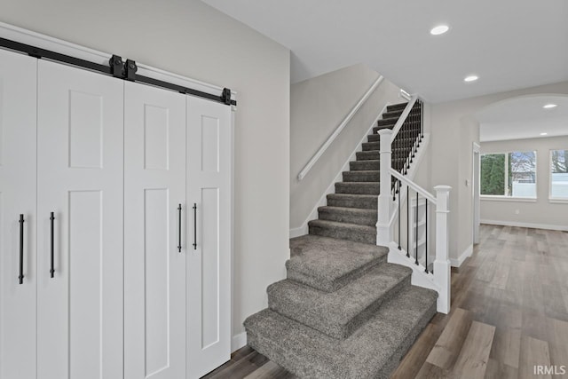 staircase featuring a barn door and hardwood / wood-style floors