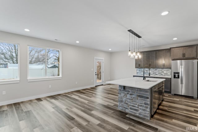 kitchen with decorative light fixtures, sink, a kitchen island with sink, dark brown cabinetry, and stainless steel appliances