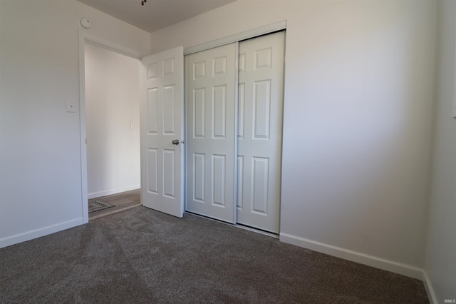 unfurnished bedroom featuring a closet and dark colored carpet