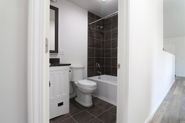 full bathroom with tile patterned flooring, tiled shower / bath, vanity, and toilet