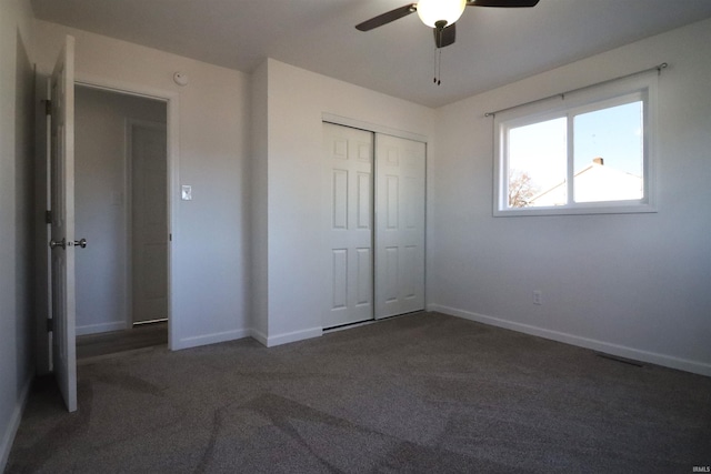 unfurnished bedroom with ceiling fan, dark carpet, and a closet