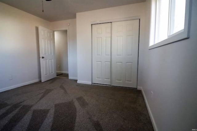 unfurnished bedroom with a closet and dark colored carpet