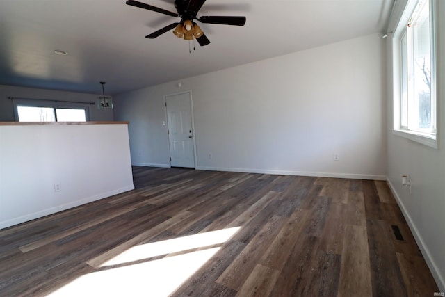 empty room with ceiling fan, plenty of natural light, and dark hardwood / wood-style flooring